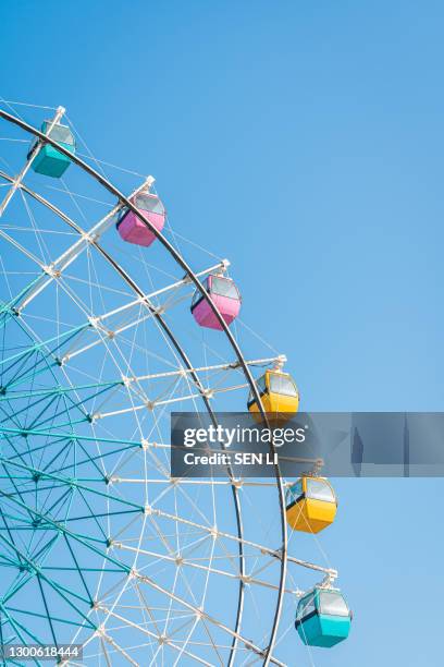 colorful ferris wheel in an amusement park against blue sky - ferris wheel foto e immagini stock