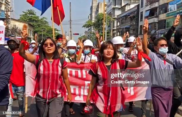 In this screengrab taken from a video shot by the photographer, protesters march along a street while shouting slogans and holding up three-finger...