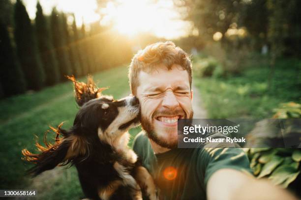 junger mann spielt mit einem hund und macht selfie - hund stock-fotos und bilder