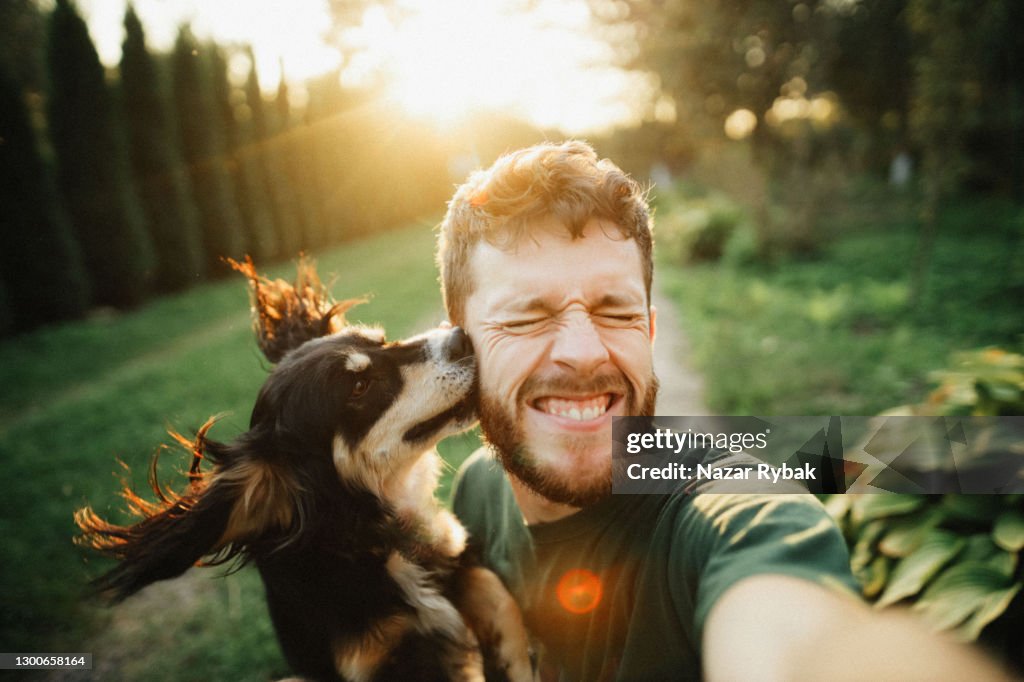 Joven está jugando con un perro y hacer selfie