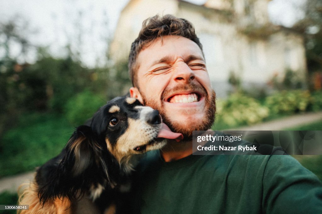 Joven está jugando con un perro y hacer selfie