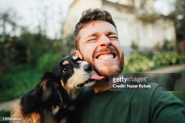 young man is playing with a dog and do selfie - cheerful stock pictures, royalty-free photos & images