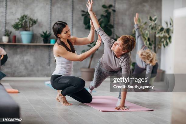 yoga instructor with senior women on yoga class - yoga instructor stock pictures, royalty-free photos & images