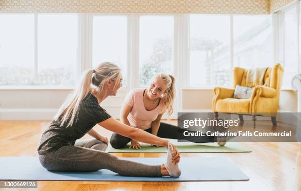 two woman stretch in a home environment - hamstring stock pictures, royalty-free photos & images