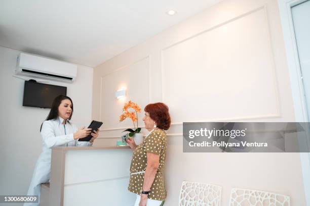 receptionist receiving patient's document - elderly receiving paperwork stock pictures, royalty-free photos & images