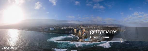 aerial panorama of puerto de la cruz resorts and pools surrounded by sea waves, tenerife, canary islands, spain. - puerto de la cruz tenerife stock pictures, royalty-free photos & images