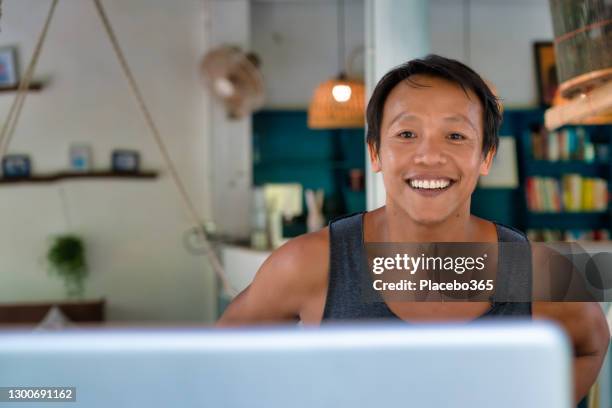happy thai man making video call from laptop at home - makeshift shelter stock pictures, royalty-free photos & images