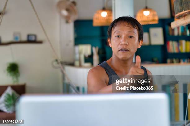 asian man giving thumbs up during video call at home - makeshift shelter stock pictures, royalty-free photos & images