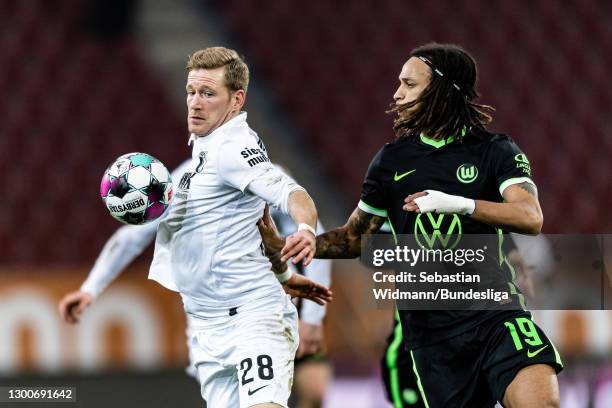 Andre Hahn of FC Augsburg and Kevin Mbabu of VfL Wolfsburg compete for the ball during the Bundesliga match between FC Augsburg and VfL Wolfsburg at...