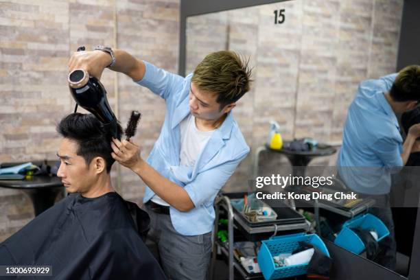 asian chinese hairdresser, drying man's hair in his saloon. - hair color saloon stock pictures, royalty-free photos & images