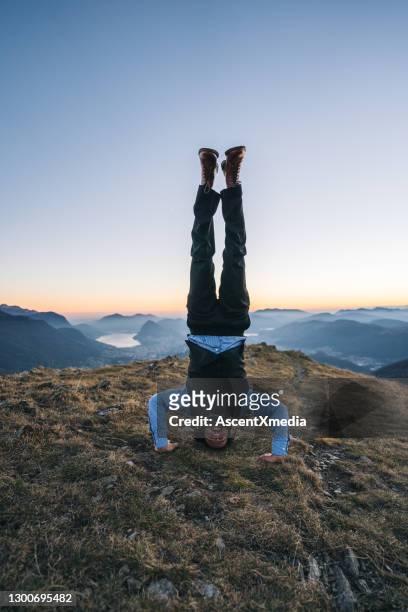 de slim geklede mens houdt handstand in bergen, dageraad - viewpoint stockfoto's en -beelden