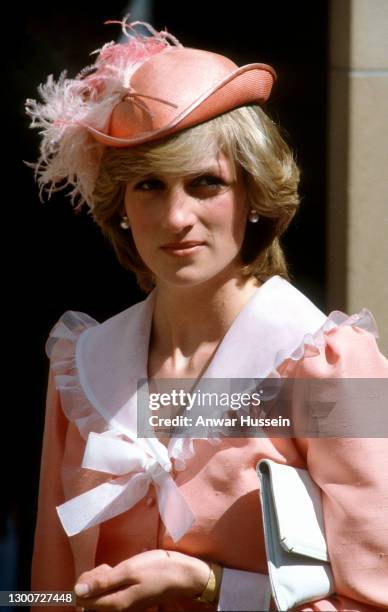 Diana, Princess of Wales, wearing a peach coloured dress with a white collar designed by Bellville Sassoon and a peach archer style hat with a...