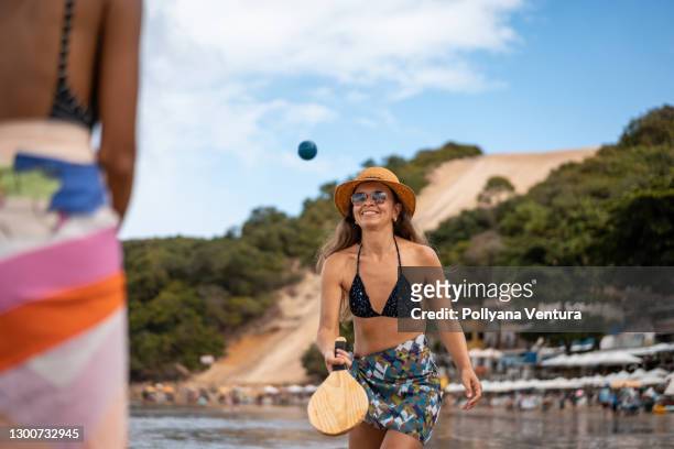 women playing paddleball on beach - sarong stock pictures, royalty-free photos & images