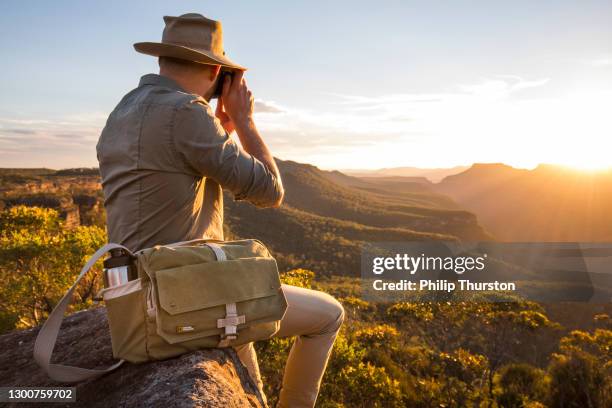 man photographing sunset atop a mountain range with photographic equipment - top of the mountain australia stock pictures, royalty-free photos & images