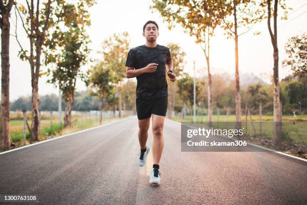south east asian sport man jogging outdoor at countryside - scoring run stock-fotos und bilder