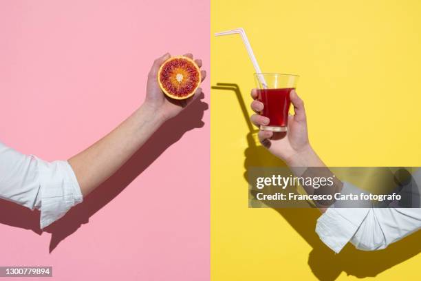 hands showing halves of red orange fruit and a glass of orange juice - hand glasses stockfoto's en -beelden