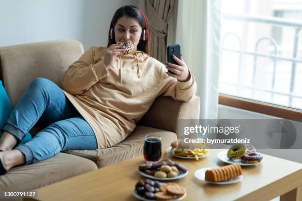 jovem comendo junk food em casa - fat people eating donuts - fotografias e filmes do acervo