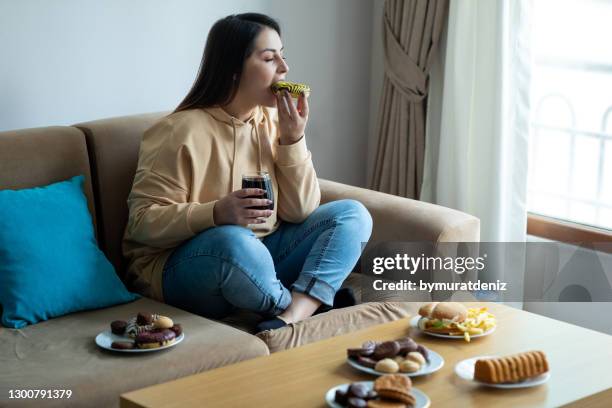 comer alimentos azucarados en el sofá - fat fotografías e imágenes de stock