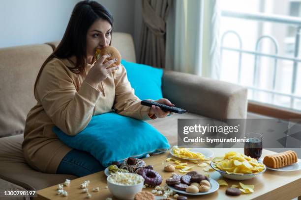 übergewichtige frau sitzt auf sofa - eating fast food stock-fotos und bilder