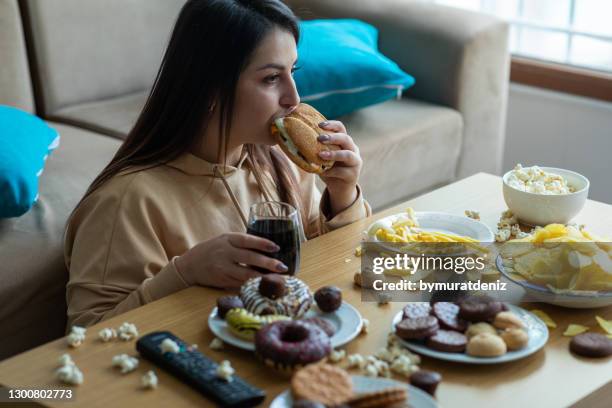 overweight young woman eating junk food - unhealthy living stock pictures, royalty-free photos & images