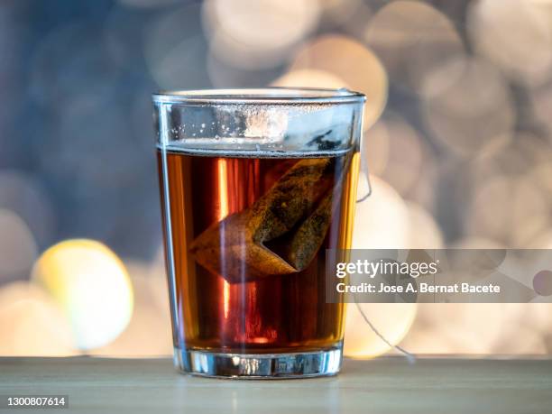 crystal glass with an infusion of red tea, (tea bag) on a wooden table. - crystal glasses stockfoto's en -beelden