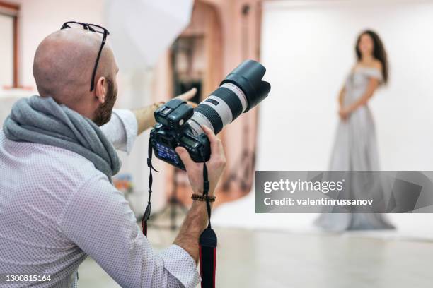 de fotograaf die van de manier een fotozitting met een model in een studio ontspruit - picture magazine stockfoto's en -beelden
