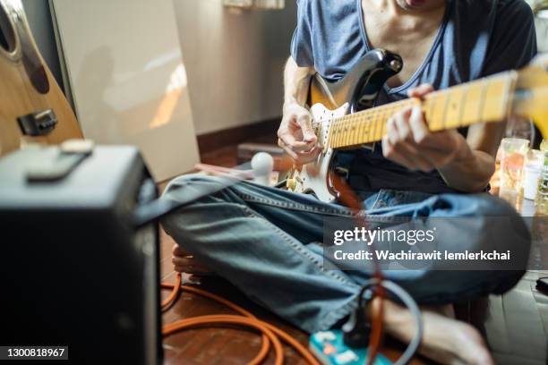 a man playing an electric guitar plugged into an amp - electric guitarist stock pictures, royalty-free photos & images