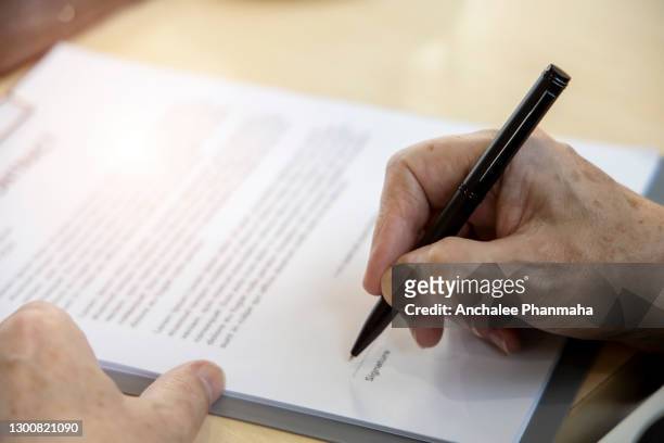 business concept:  close up picture of the senior businessman is sign the document in the office - parte del cuerpo humano fotografías e imágenes de stock