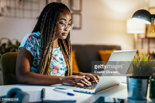 mulher afro-americana trabalhando até tarde da noite no laptop - educational subject - fotografias e filmes do acervo