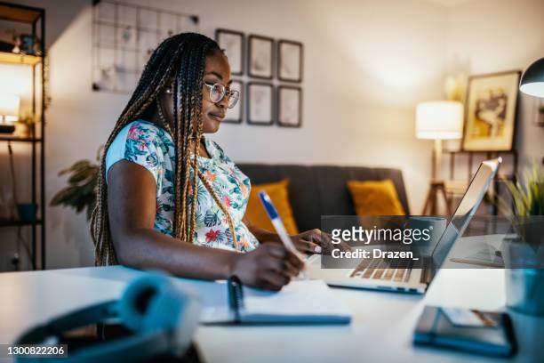 estudiante afroamericana estudiando desde casa y tomando notas de la profesora - homework fotografías e imágenes de stock