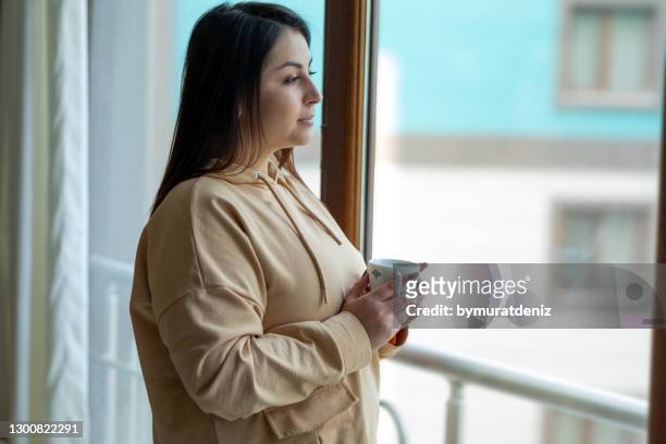 woman standing near window - big fat women stock pictures, royalty-free photos & images