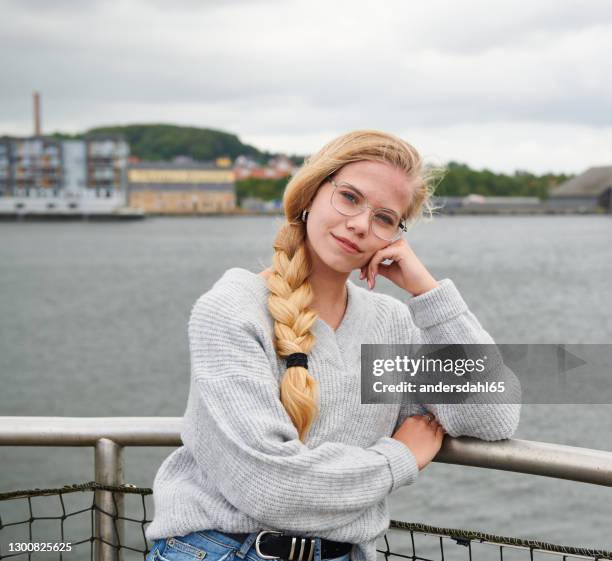 pensive woman in gray sweater leaning on hand on fence of boat in river - andersdahl65 stock pictures, royalty-free photos & images