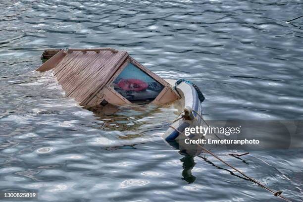 half sunken wooden fishing boat,inciaralti marina. - sunken stockfoto's en -beelden