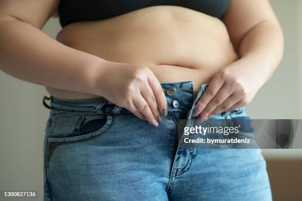 cercando di indossare jeans attillati - human abdomen foto e immagini stock
