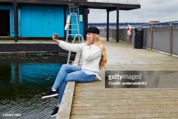 charming young woman in beret taking selfie on poolside - andersdahl65 stock pictures, royalty-free photos & images