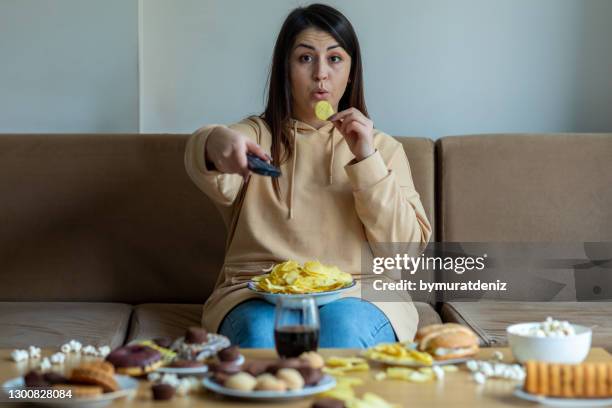overweight woman sit on the sofa with junk food - unhealthy living stock pictures, royalty-free photos & images