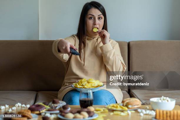 overweight woman sit on the sofa with junk food - binge eating stock pictures, royalty-free photos & images