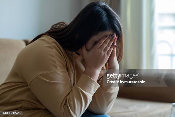 donna triste seduta su un divano nel soggiorno - dipendenza foto e immagini stock