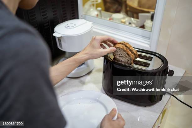 a man toasts sourdough bread with bread toaster - トースター ストックフォトと画像