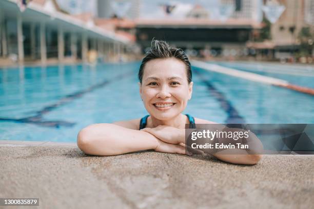 aziatische chiinese rijpe vrouw die camara bij het zwembad bekijkt - early retirement stockfoto's en -beelden