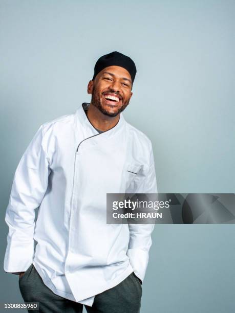 alegre chef masculino sobre fondo gris - uniforme de chef fotografías e imágenes de stock