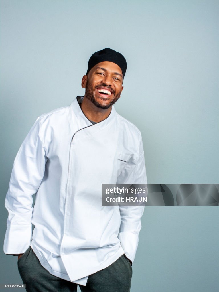 Vrolijke mannelijke chef-kok op grijze achtergrond