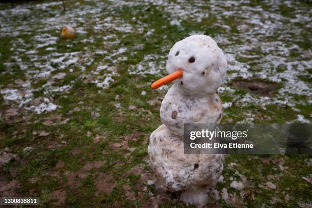 snowman standing in slowly melting snow in a back yard - melted snowman stock-fotos und bilder