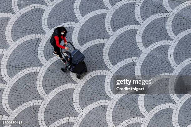 mother wearing face mask walking baby in stroller - cobblestone pattern stock pictures, royalty-free photos & images