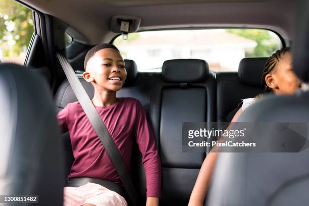 feliz niño y hermana en el asiento trasero de los cinturones de seguridad del coche en - cinturón de seguridad fotografías e imágenes de stock