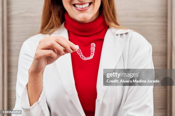 young female dentist showing an invisible dental aligner. medical concept. - invisible braces stock pictures, royalty-free photos & images