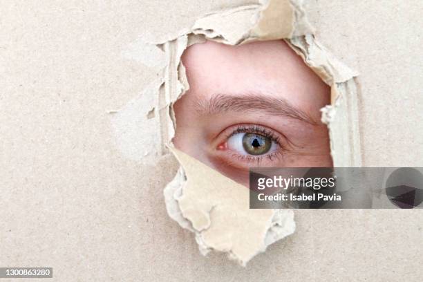 young woman looking through a hole on cardboard - spain teen face stock-fotos und bilder