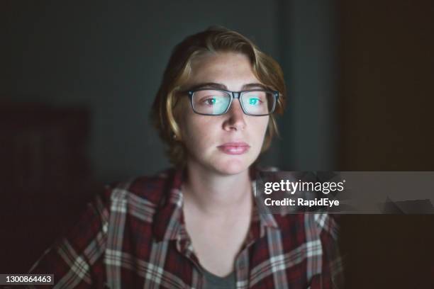 young woman in glasses and checked shirt working late on her computer at night - staring at screen stock pictures, royalty-free photos & images