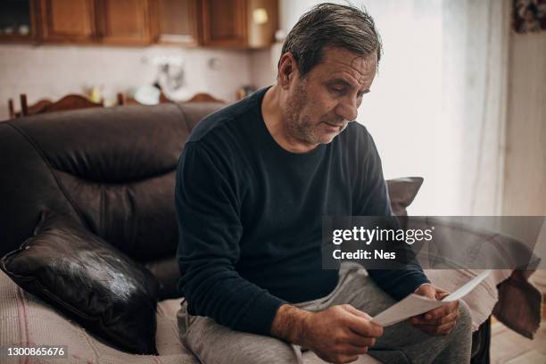 a depressed old man reads a letter - crisis response stock pictures, royalty-free photos & images