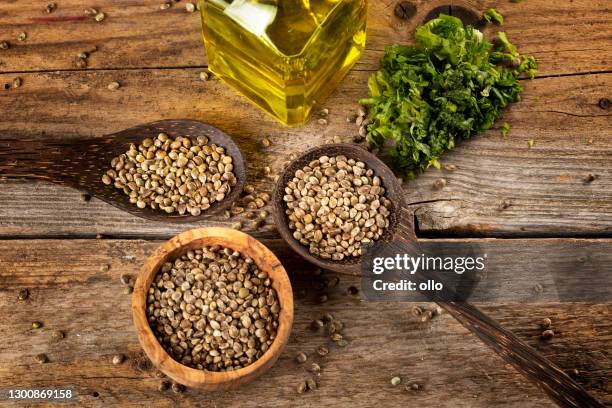 semilla de cáñamo en cucharas de madera y aceite sobre mesa de madera rústica - hemp seed fotografías e imágenes de stock